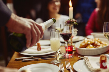 This calls for a celebration. Closeup shot of a person pouring wine into a glass at a dining table.