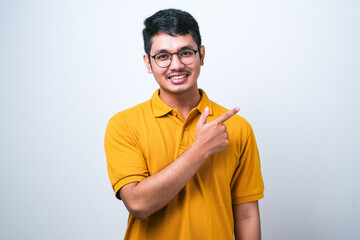 Asian man wearing casual shirt over white background with a big smile on face, pointing with hand finger to the side looking at the camera.