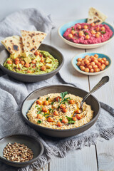 Various vegan hummus dips red beetroot green avocado and traditional chickpea.Traditional vegan hummus variety red beetroot green avocado and yellow chickpea with chia and sunflower seeds. Vegan diet 