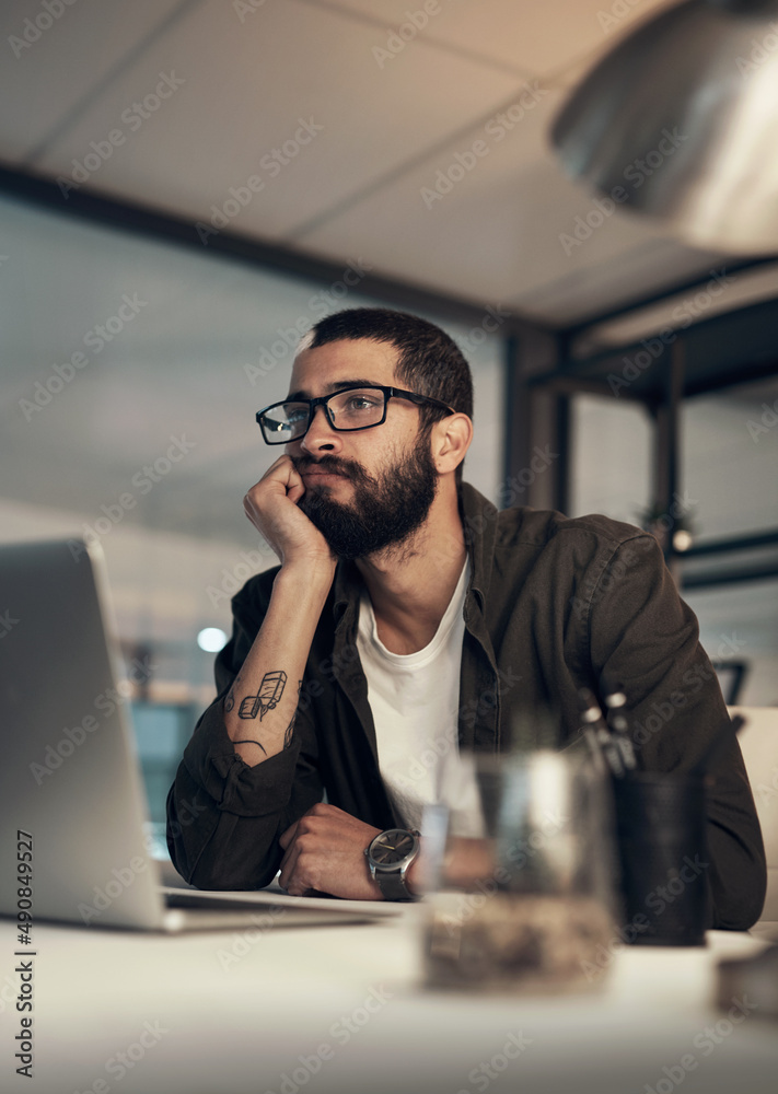 Poster better finish up before i fall asleep. shot of a young businessman looking uncertain while working l