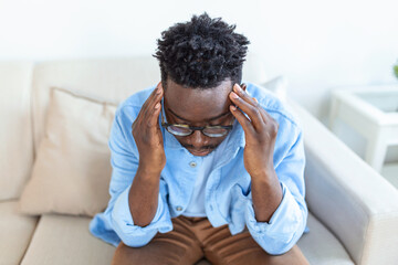 Tired African American man taking off glasses, exhausted massaging nose bridge, suffering from eye strain after long computer work, feeling pain, health problem concept