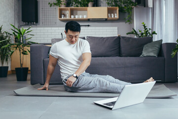 Asian man at home, engaged in fitness online, uses laptop for joint activities, active lifestyle