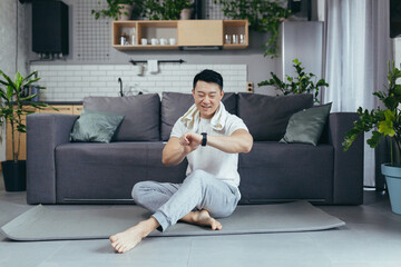 Obraz premium Happy man is resting after morning exercise, Asian is doing fitness at home on a sports mat