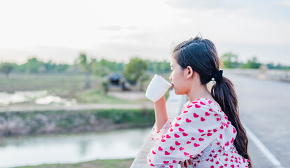 Close-up of a smiling woman sipping coffee from a white mug.