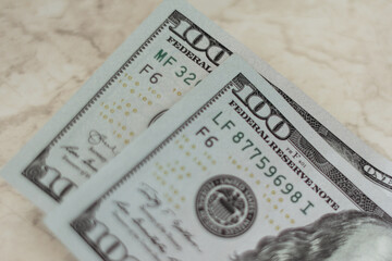 Two paper bills with a face value of one hundred dollars. Close-up