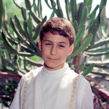 Portrait of a cute boy wearing a white tunic. Altar boy, choirboy.