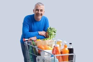 Smiling man posing with a shopping cart
