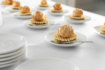 Many delicious waffles with cream served on white table for coffee break