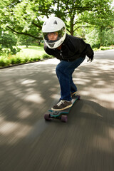 Building up speed. Shot of a man skateboarding down a lane at high speed on his board.