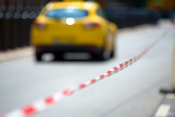 Barrier tape on a street against defocused taxi