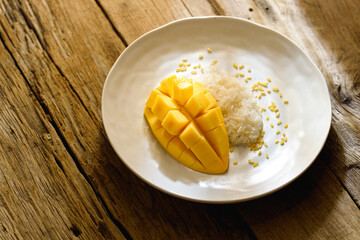 Thai Mango Sticky Rice, Southeast Asian dessert white plate on wooden table top