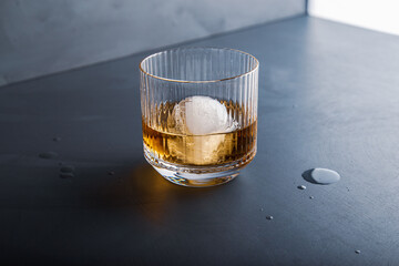 Sphere shaped ice cube and close up whiskey view from studio.