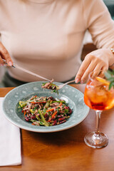Woman puts salad on a fork in a restaurant
