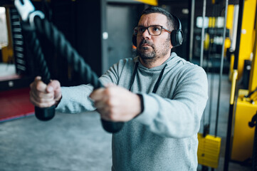 Middle aged men using a cross machine in the gym