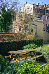 Picnic area in the park of Venice. Table with benches in the middle of the bushes with the backdrop of Venetian houses. Vertical image.