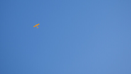 Light aircraft flies in the clear blue sky. Wallpaper or background. Yellow small plane. General aviation. Air sports and tourism