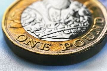 The British one pound sterling coin is lying on paper textured surface. Bright illustration about economy and money in England. Focus is on inscription with nominal value and name of the UK currency