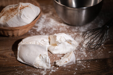 Une grosse meringue cassée sur une table de cuisine avec un fouet, un bol et du sucre