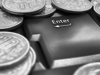 Japanese money coins and Enter button close up. Coins in 10 yen lie on keyboard of a computer or laptop. Black and white illustration about online trading, payments and transfers in Japan. Macro