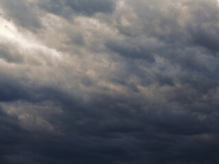 Obraz premium Dark gray heavy clouds in the sky before a thunderstorm. Dramatic spectacular backdrop or wallpaper. Natural grim menacing background. Ahead of a storm or cataclysm. Beastly nasty weather. Overcast