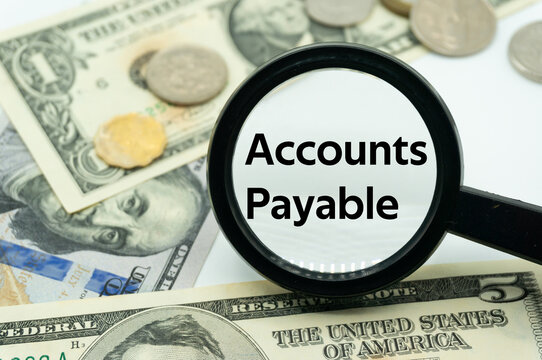 Magnifying glass showing the words "Accounts Payable".Background of banknotes and coins.A/P or AP.Trade Payable.Financial Concept.