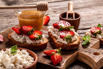 toasts or bruschetta with strawberry and mint on cream cheese ricotta. Delicious breakfast or snack, top view