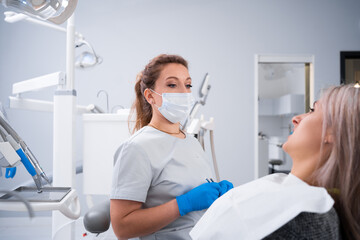 Fototapeta na wymiar A female dentist in a dental office is talking to a patient and getting ready for treatment.