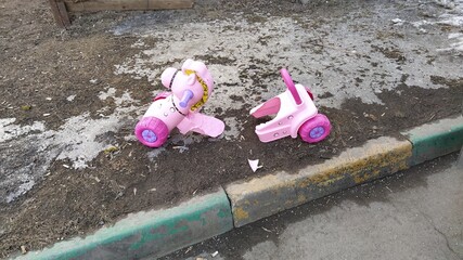 broken toy. baby pink horse on wheels broke on the road