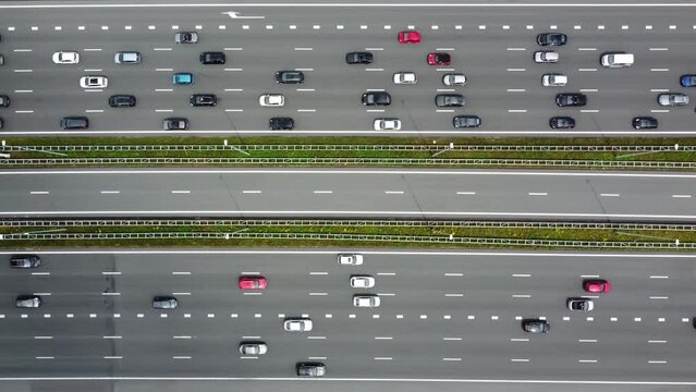 Speeded up aerial top down footage of highway with vehicles moving in both ways on one side of the motorway with a congestion and on the other way free movement of traffic 4k high resolution