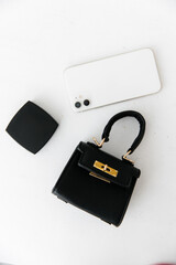 Fashionable women's handbag. fashionable women's accessory. clutch bag with gold hardware. powder coat and white phone on a white background. 