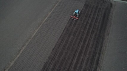 Aerial view of a tractor preparing the ground for spring agricultural work. Spring plowing.