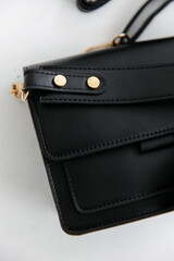 Fashionable women's small leather clutch bag with strap. Isolated on a white background. Traditional clutch bag with a brooch. Gold hardware. Close-up details of the bag. Bottom, handles, strap, clasp