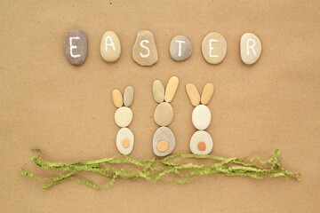 Easter lettering and bunnies from pebbles on craft paper background. Ecological, eco friendly, zero waste nature concept. Flatlay, lay out, top view