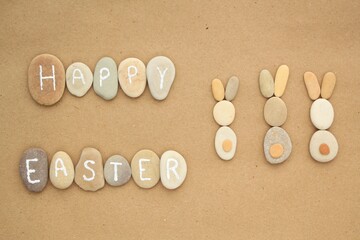 Fototapeta na wymiar Happy Easter lettering and bunnies from pebbles on craft paper background. Ecological, eco friendly, zero waste nature concept. Flatlay, lay out, top view