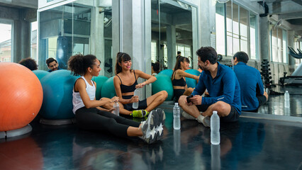Fototapeta premium Healthy athletic man and woman in sportswear relaxing and drinking water after workout exercise together at gym. Male and female do sport training at fitness club. Health care motivation concept