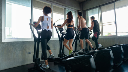 Fototapeta na wymiar Group of Healthy athletic man and woman in sportswear workout exercise on cycling machine together at fitness gym. Male and female do sport training at sport club. Health care motivation concept
