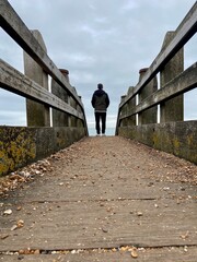 wooden boardwalk man looking at sea ocean. Wooden jetty path at Baltic sea over sand dunes with ocean view, evening