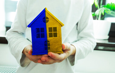 Kid holding wooden toy house in Ukrainian flag colors