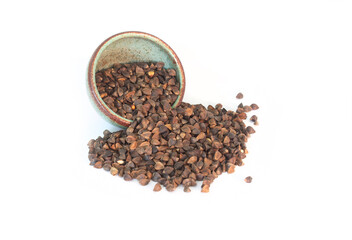 Organic Buckwheat Whole and Unhulled Seeds Spilled from Green Pottery Bowl Isolated on White