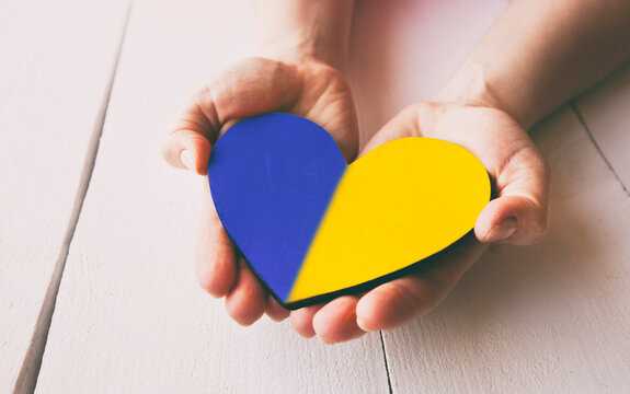 The wooden heart in colors of Ukrainian flag in woman's hands
