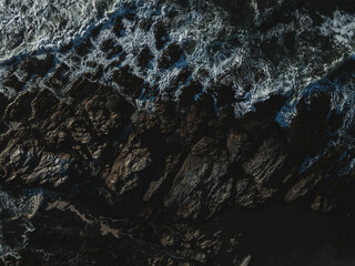 Drone shot of the sea waves hitting the rocks