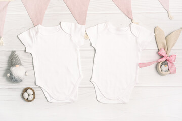 Two white baby bodysuit mockup with Easter decor on white wood background. Easter eggs and gnome...