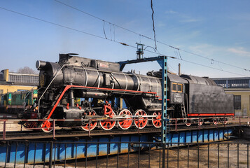 Fototapeta na wymiar Vintage black steam locomotive. Old Soviet steam train in the depot. Space for text. Background with a steam train.