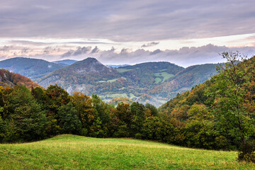 Mountain landscape with cloudy sky and forest in the foreground. Beautiful hills. View from above. Late autumn. Vrsatec, Slovakia.