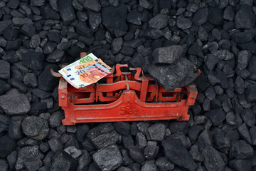 European currency euro and coal showed on weight as concept on coal of mine deposit mineral resources background