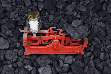  White graveyard candle and coal showed on weight as concept on coal of mine deposit mineral resources background
