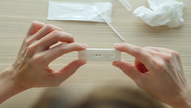 Self test of Coronavirus infected patient using ATK rapid test kit to check the positive result at home. Close up shot of woman holding antigen test kit with stress feeling to know the 2 stripe result
