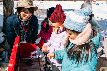 キャンプで焼きマシュマロを作る子供たち