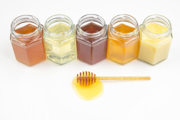 spoon with fresh honey and pollen on the background of jars with different types of honey. organic vitamin food