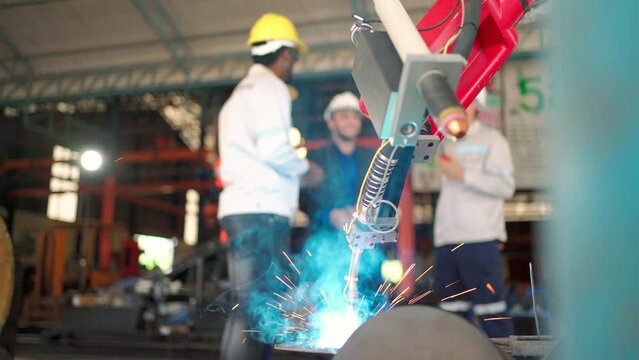 Industrial automate modern robotic welding arm machine tool welds metal and plate. Bright sparks and smoke in the production line at Robotic manufacturing with engineer background. Technology and Ai